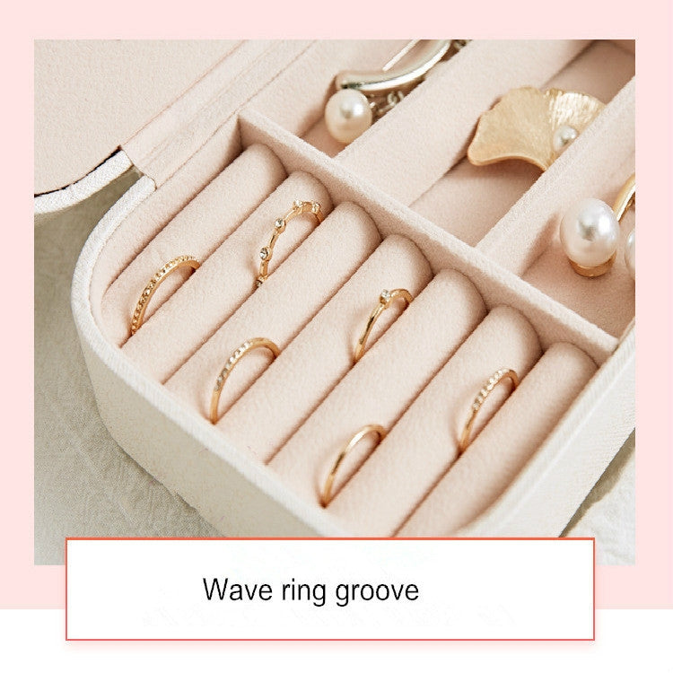 Open jewelry box with cushioned ring slots and small earring holders inside.