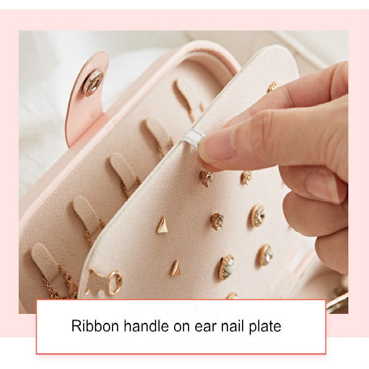 Open jewelry box with earring plate and ring being placed by hand.