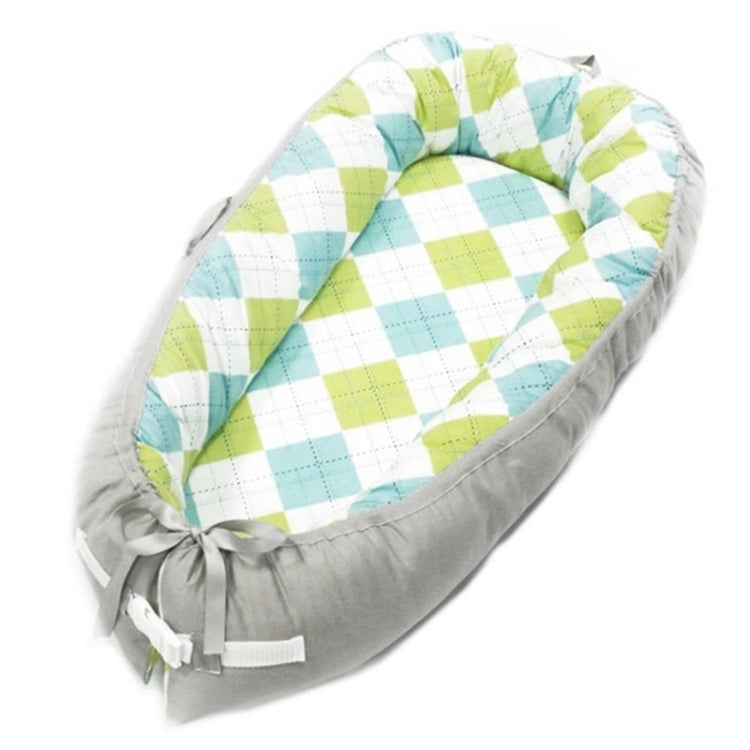 Portable baby nest with gray sides and aqua-lime checkered inner cushion, tied bow