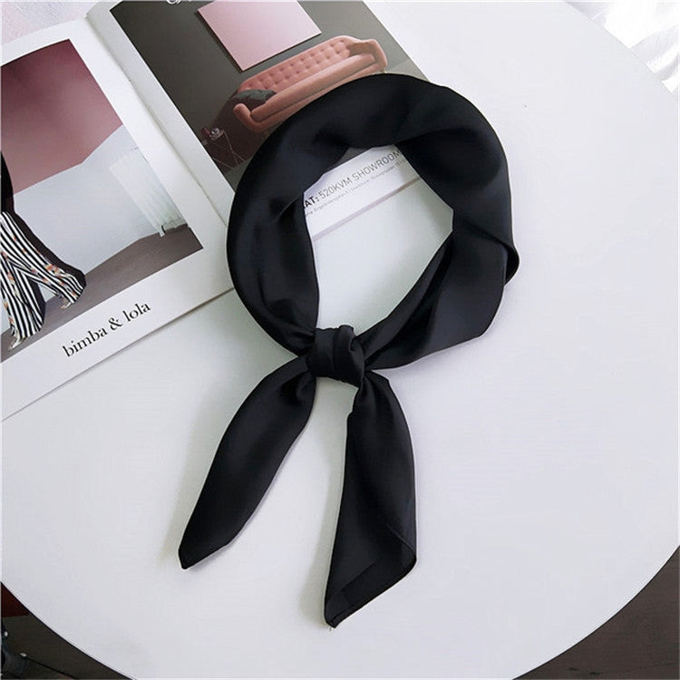 Black square satin scarf tied into a neck scarf with trailing bow