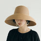 Beige straw sun hat with wide brim and curved crown on a model