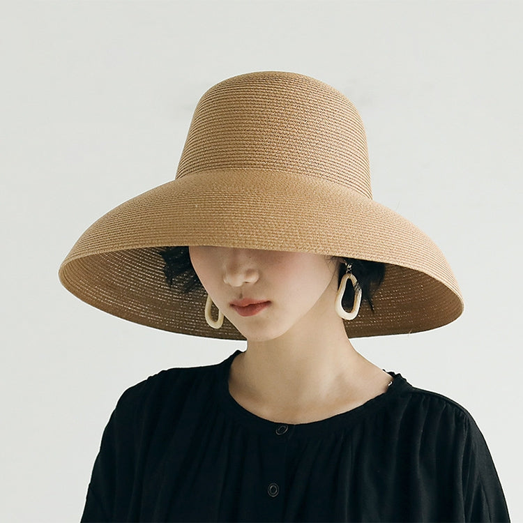 Beige straw sun hat with wide brim and curved crown on a model