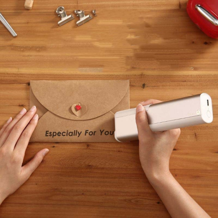 White portable printer pen applying printed design on kraft envelope
