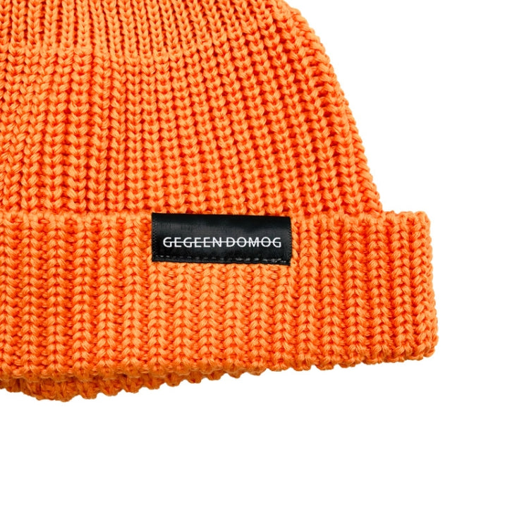 Orange short knit beanie with folded cuff and rectangular logo patch