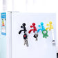 Colorful humanoid magnet key hangers with attached metal keys on a refrigerator.