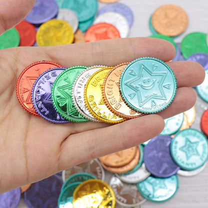 Hand holding assorted seven-color lucky pirate coin tokens, close-up of embossed designs