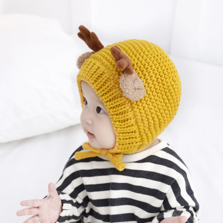 Side view of yellow knitted baby hat with brown antler and ear-flap appliques