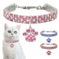 Pink rhinestone pet collar with paw charm and clasp, shown on a cat
