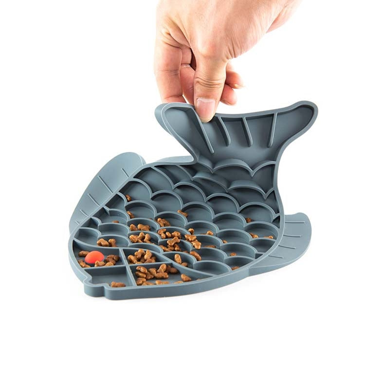 Gray silicone paw-print slow food mat with food compartments, held open by a hand
