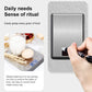 Digital kitchen scale with brushed stainless platform and hand pressing the button