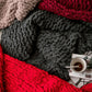Close-up of thick chunky knit wool blanket texture in gray and deep red