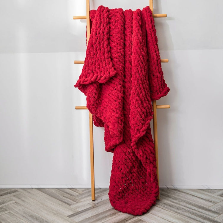 Red chunky cable-knit wool blanket with thick textured weave, draped on a stand