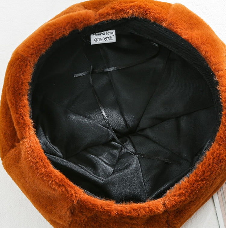 Plush beret hat with black inner lining, caramel/orange fuzzy outer.