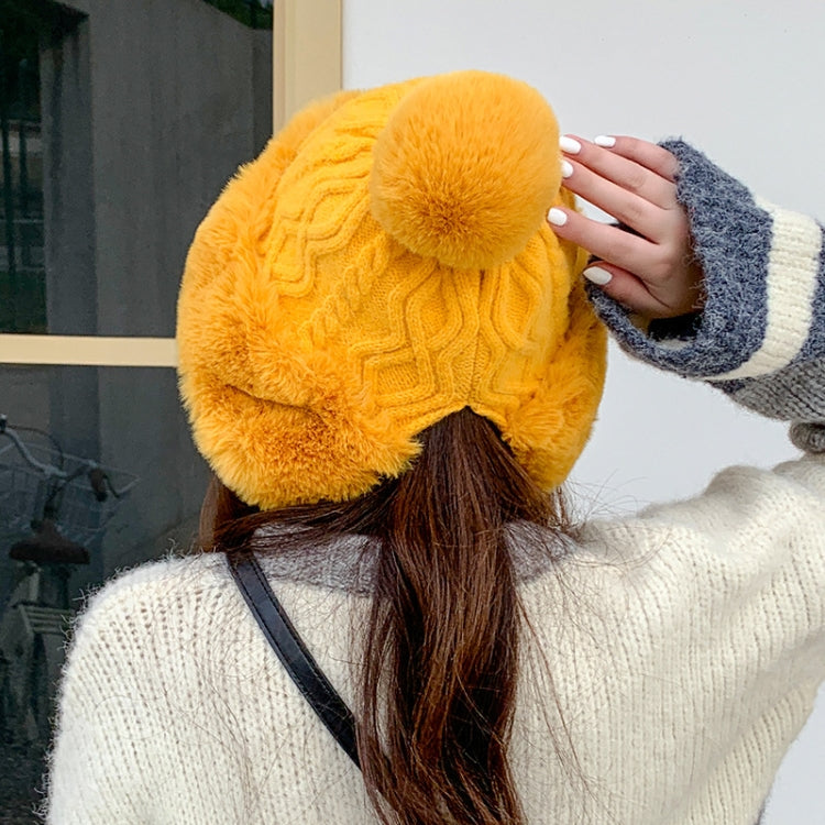 Mustard knit beanie with large faux-fur pom-pom and textured swirl pattern