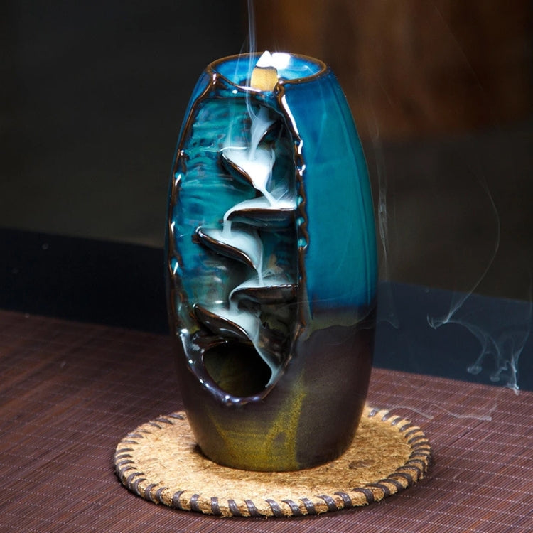 Blue ceramic lotus incense burner with rising smoke and circular base mat
