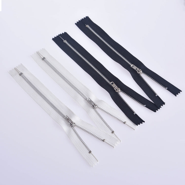 Group of zippers in white and silver tone, plus dark navy with gold-toned teeth