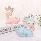 Blue and pink cartoon deer resin decorations, lying down beside stacked books