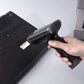 Black handheld barcode scanner gun held in hand with dark scanning window