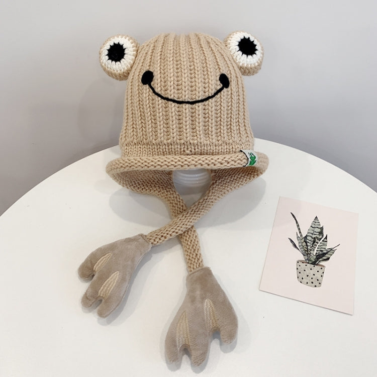 Beige knitted frog hat for toddlers with smile face, big white eyes, and long tie flaps