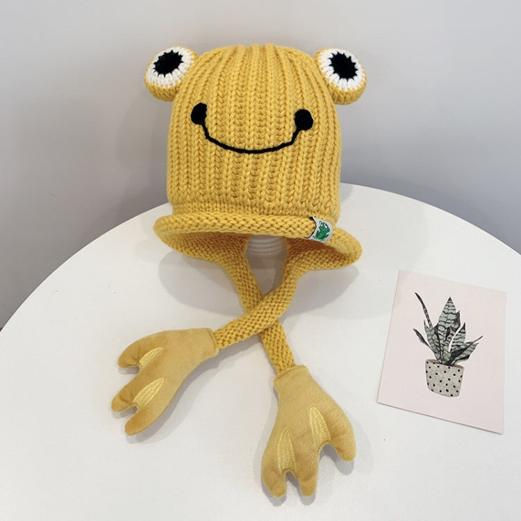 Yellow knitted frog hat for toddlers with smile face, big white eyes, and long tie flaps
