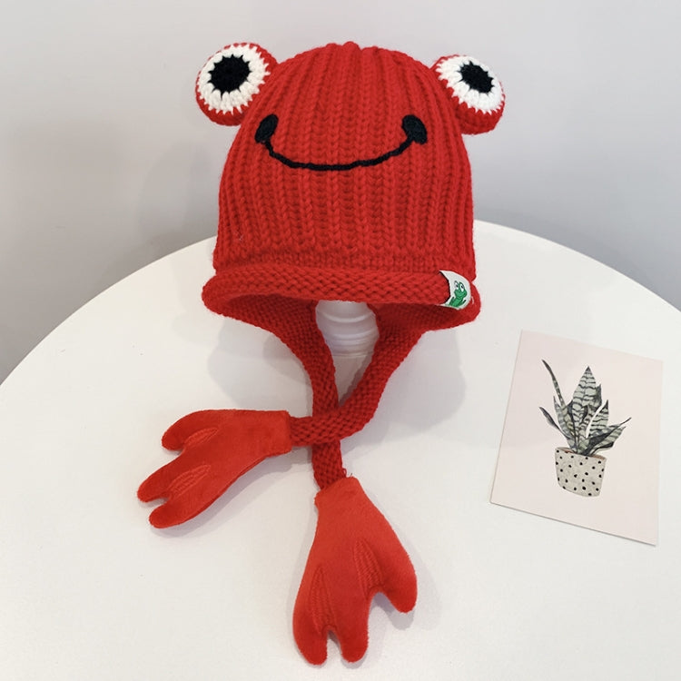 Red knitted frog hat for toddlers with smile face, big white eyes, and long tie flaps