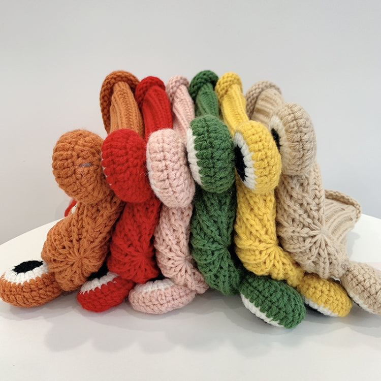Stack of knitted frog hats in mixed colors with smile face and large white-and-black eyes