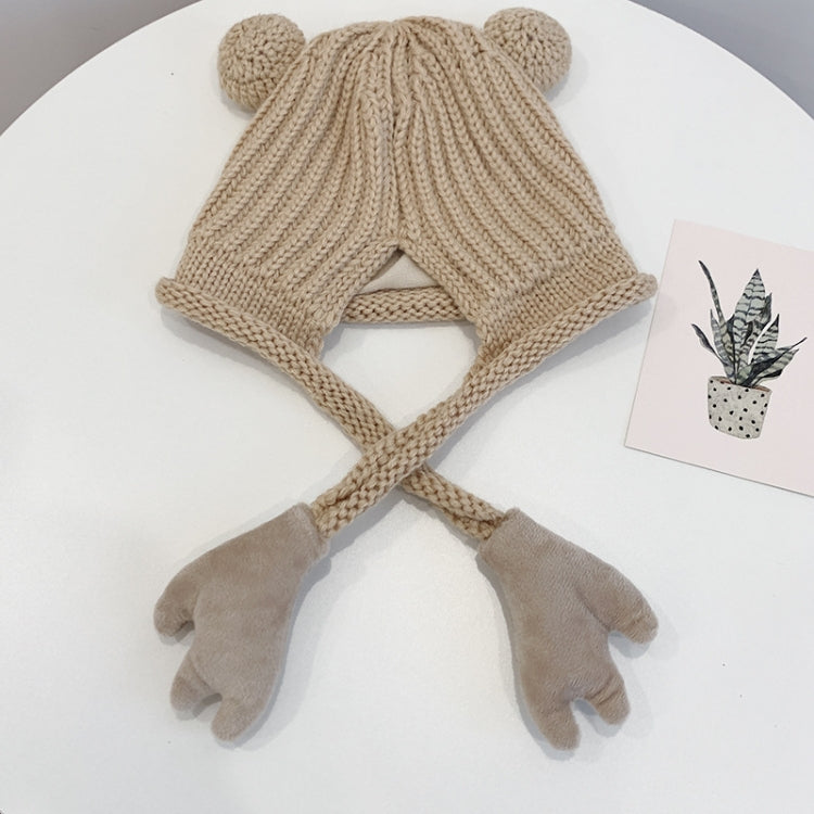 Beige knitted children winter hat with ear flaps and long tie strings