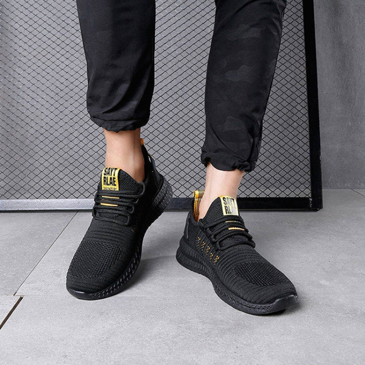 Black running sneakers on feet, lace-up with yellow accents