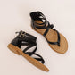 Pair of black strappy cross-strap sandals with low heel and gold-tone buckles