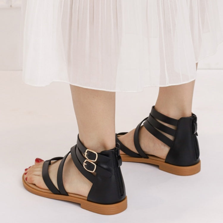 Black strappy low-heeled Roman-style sandals with crisscross straps and buckled ankle