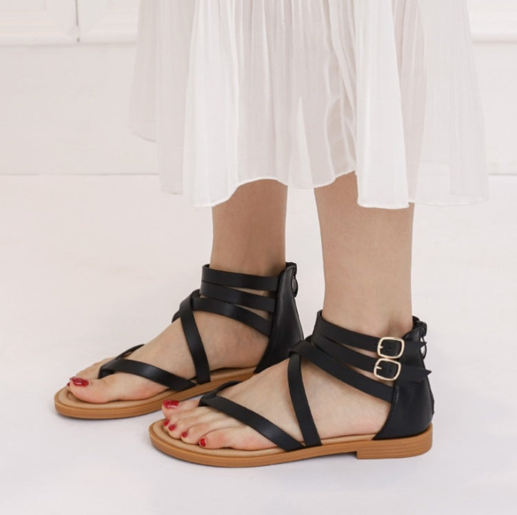 Black strappy flat sandals with open toe, multiple straps, and metal buckle detail