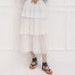 Black strappy low-heeled sandals worn with a white tiered dress