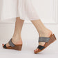 Two-strap platform wedge sandals on model, with dark grey straps and wood-look heel