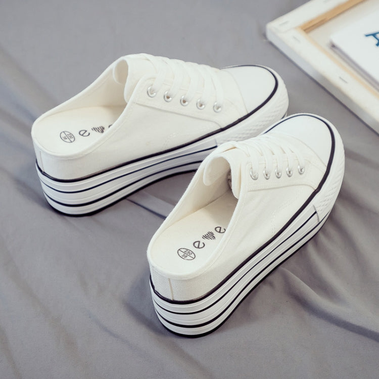 White canvas platform mule sneakers with lace-up front and thick striped sole.
