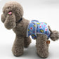 Dog anti-harassment pants with colorful blue animal print, worn by a plush brown dog.