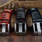 Close-up of three men’s leather belts: red, dark, and black with silver pin buckles