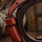 Close-up of red two-layer leather belt with stitched texture and dark pin-buckle side