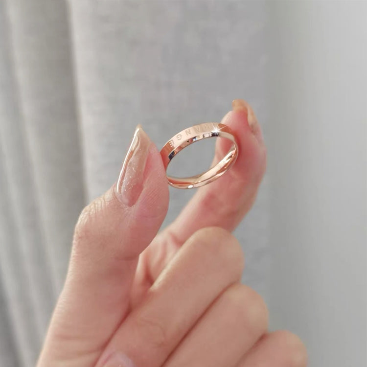 Rose gold and silver narrow rings held in hand, engraved inner text visible