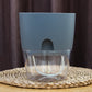 Gray transparent double-layer plastic flowerpot showing water reservoir through clear sides