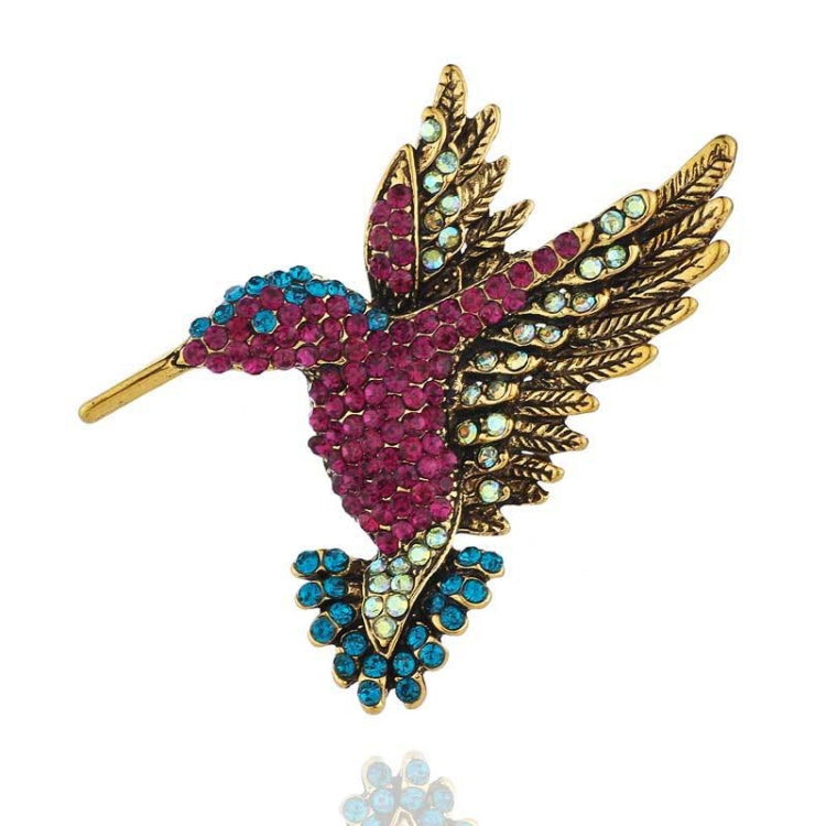 Gold-tone rhinestone bird brooch with pink and teal layered wings and pin