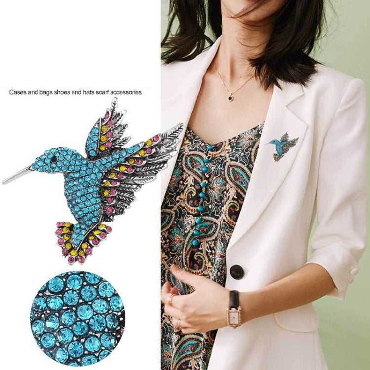 Blue rhinestone bird brooch pinned on a white blazer lapel