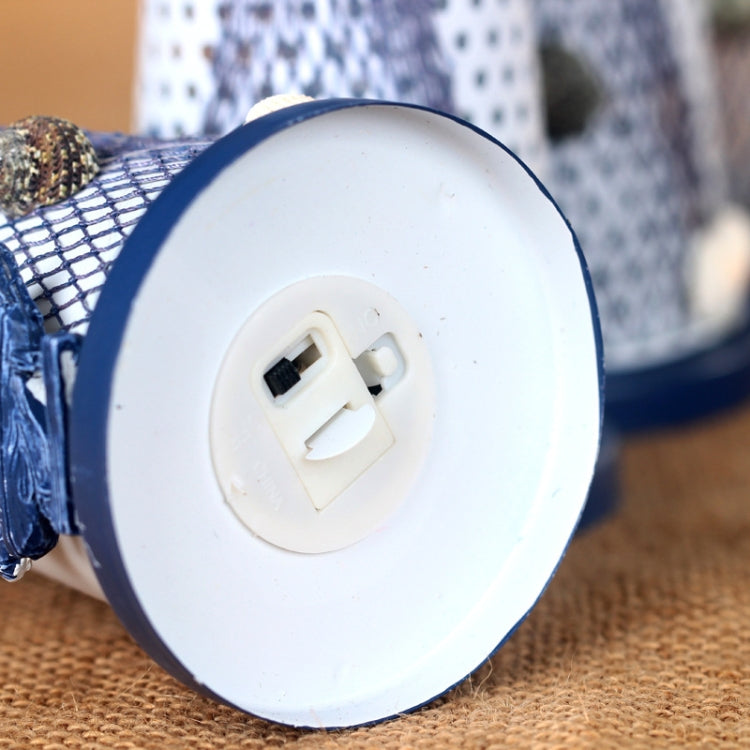 Bottom of blue and white tin lighthouse decoration with battery compartment access