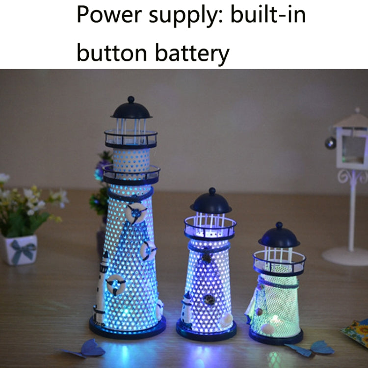 Lit blue and white tin lighthouse decoration with glowing lantern rings and small base ornaments