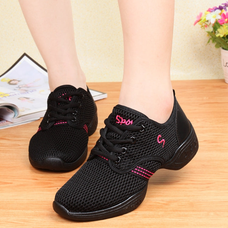 Black lace-up breathable dance shoes on feet with pink accent stripes