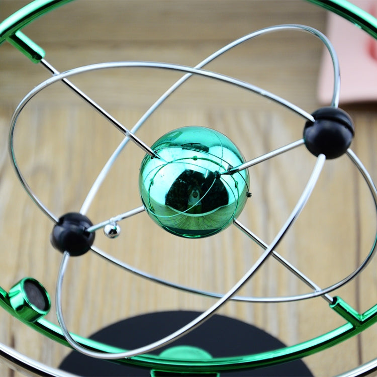 Close-up of rotating magnetic ornament with teal glass globe and metal support rods