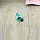 Close-up of rotating magnetic globe ornament with teal sphere and black magnetic pins