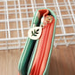 Long zipper wallet corner view with mint green trim and orange zip pocket with charm.