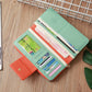 Long zipper wallet opened to show card slots, mint green exterior with orange inner panel.