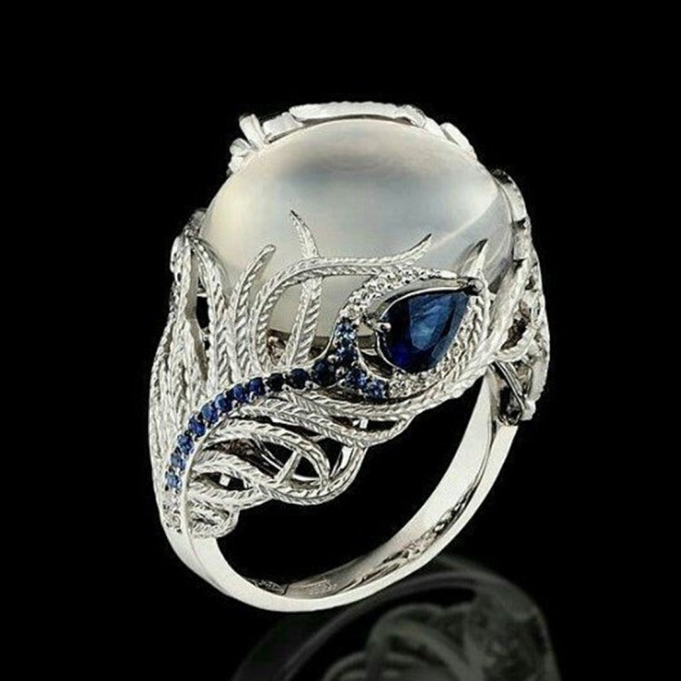 Silver-tone statement ring with oval white stone and blue gems in feather motif setting
