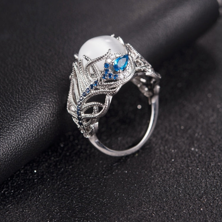 Silver-tone ring with oval white stone and blue teardrop gems, filigree feather design